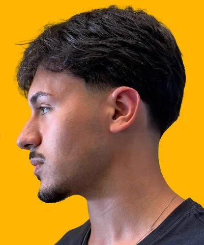 Cliente de perfil com cabelo escuro texturizado e degradê na Tesoura Barbearia